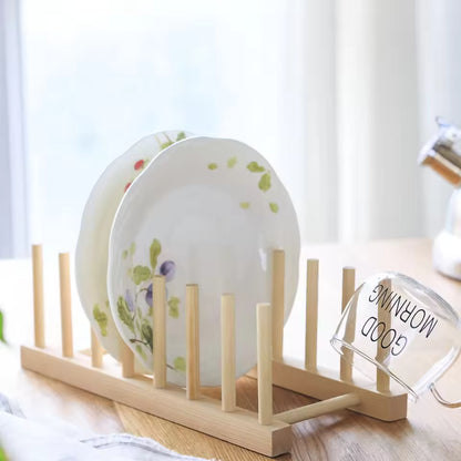 Wooden dish rack with plates and a glass on a light surface.